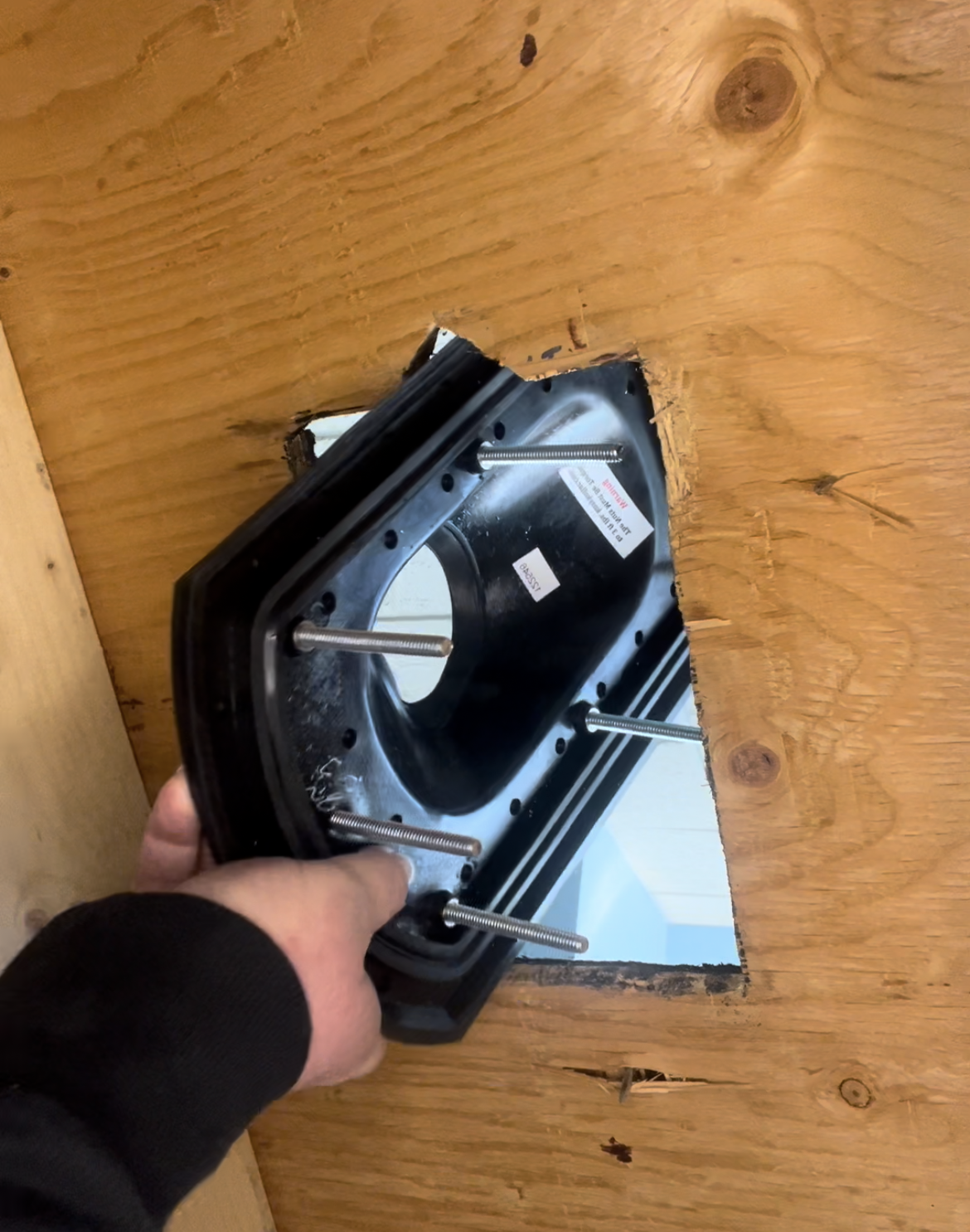 Hand holding a black mechanical component on a wooden surface
